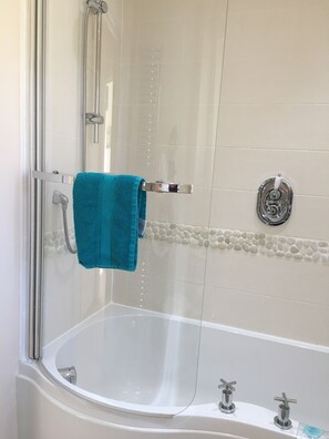 Een bad/douchecombinatie, een haardroger, handdoeken, zeep