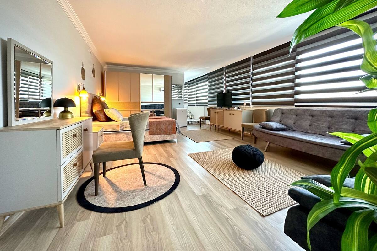 Un salon moderne comprenant un canapé, un fauteuil, un téléviseur et un bureau avec des tiroirs.