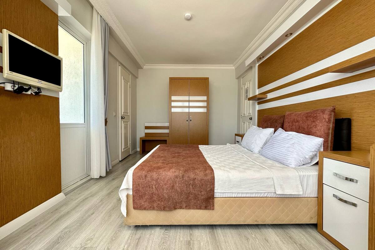 Une chambre à coucher moderne, comprenant un lit, des tables de chevet, une armoire et un téléviseur.