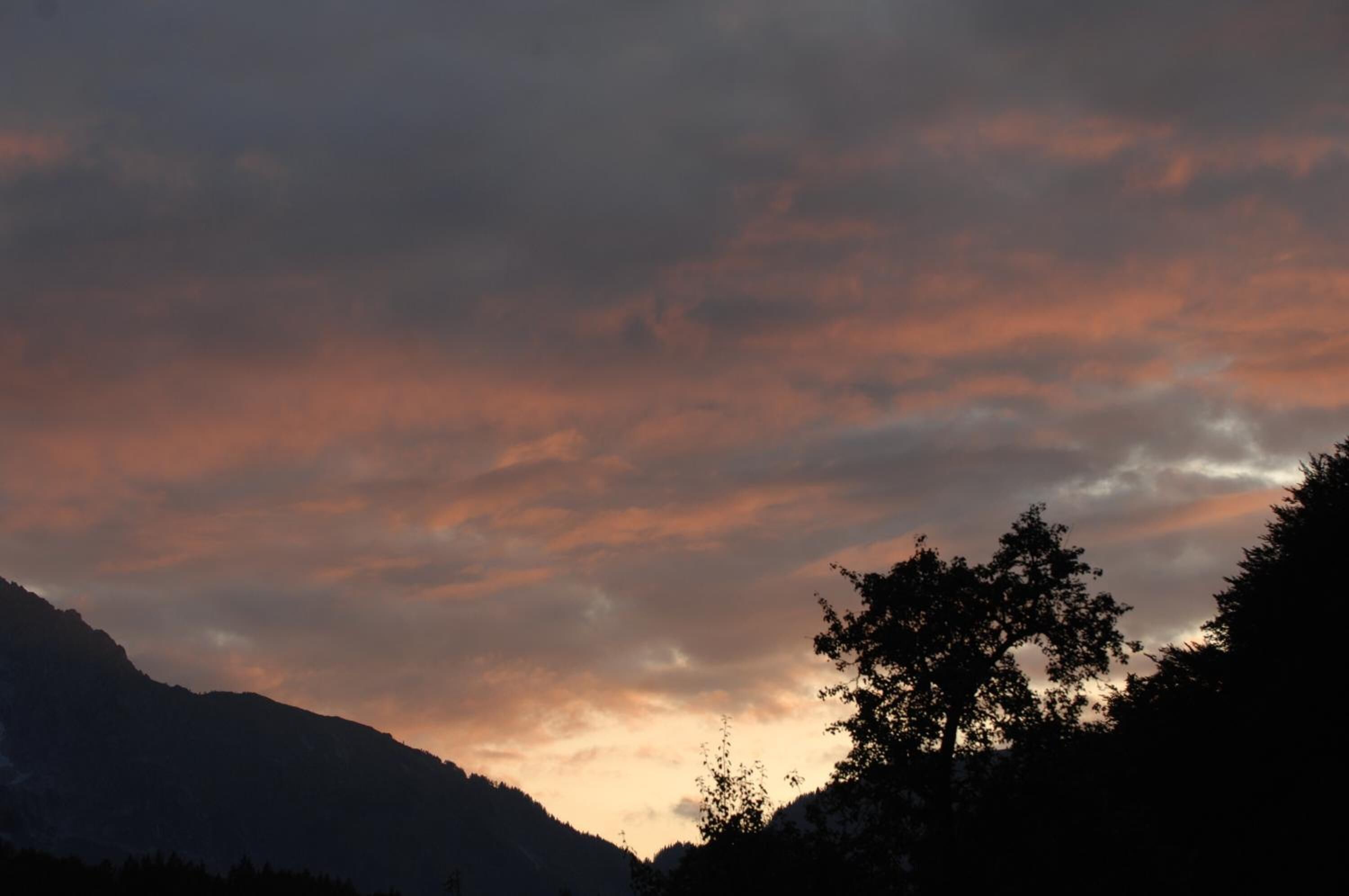 Un paysage de montagne avec un ciel au coucher du soleil.