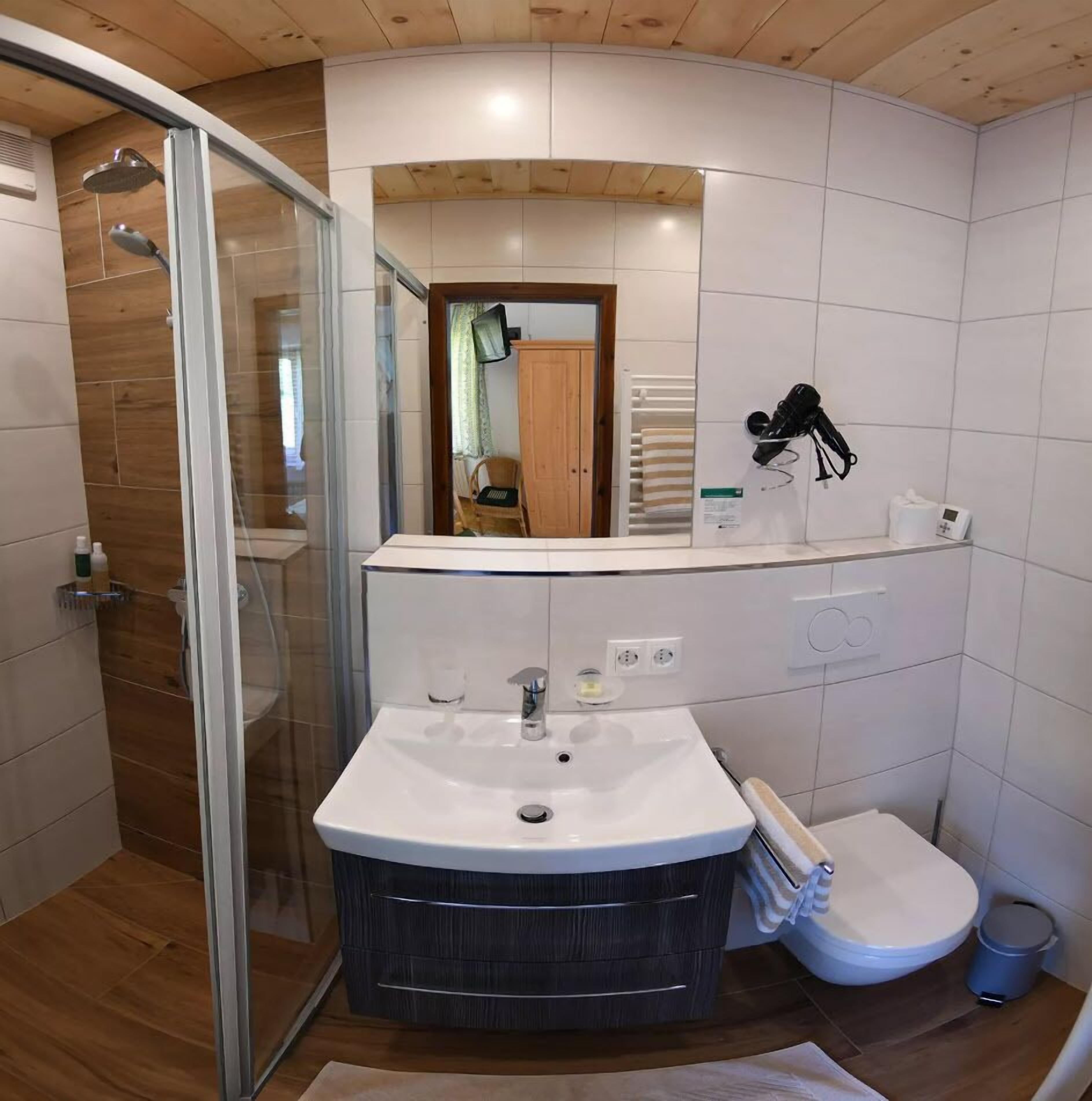 A modern bathroom with a glass shower enclosure, a vanity with a sink, and a toilet.