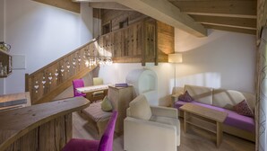 A cozy living room with a wooden staircase, a sofa, a small table, and a chair. - Feriengut Unterhochstätt (Schwendt)
