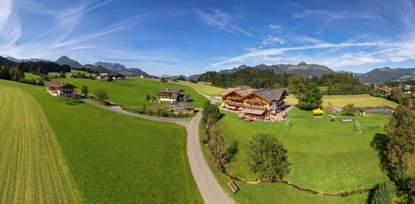 Ein großes Haus mit großzügigem Außenbereich, umgeben von üppigen grünen Feldern und Bergen im Hintergrund.