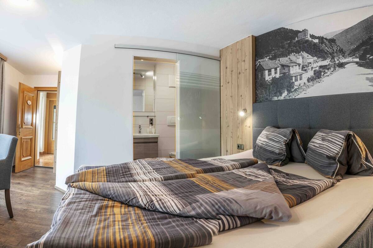 Una habitación de hotel moderna con una cama grande, un escritorio y una televisión.