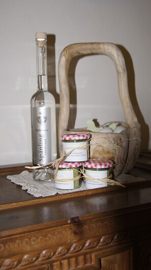 A bottle of Kobeler's brand, a wooden basket, and jars of Himalayan salt on a wooden surface.