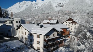 A snow-covered mountain village with traditional chalet-style buildings, a clear sky, and a winding road. - Landhaus Zangerl (Landeck)