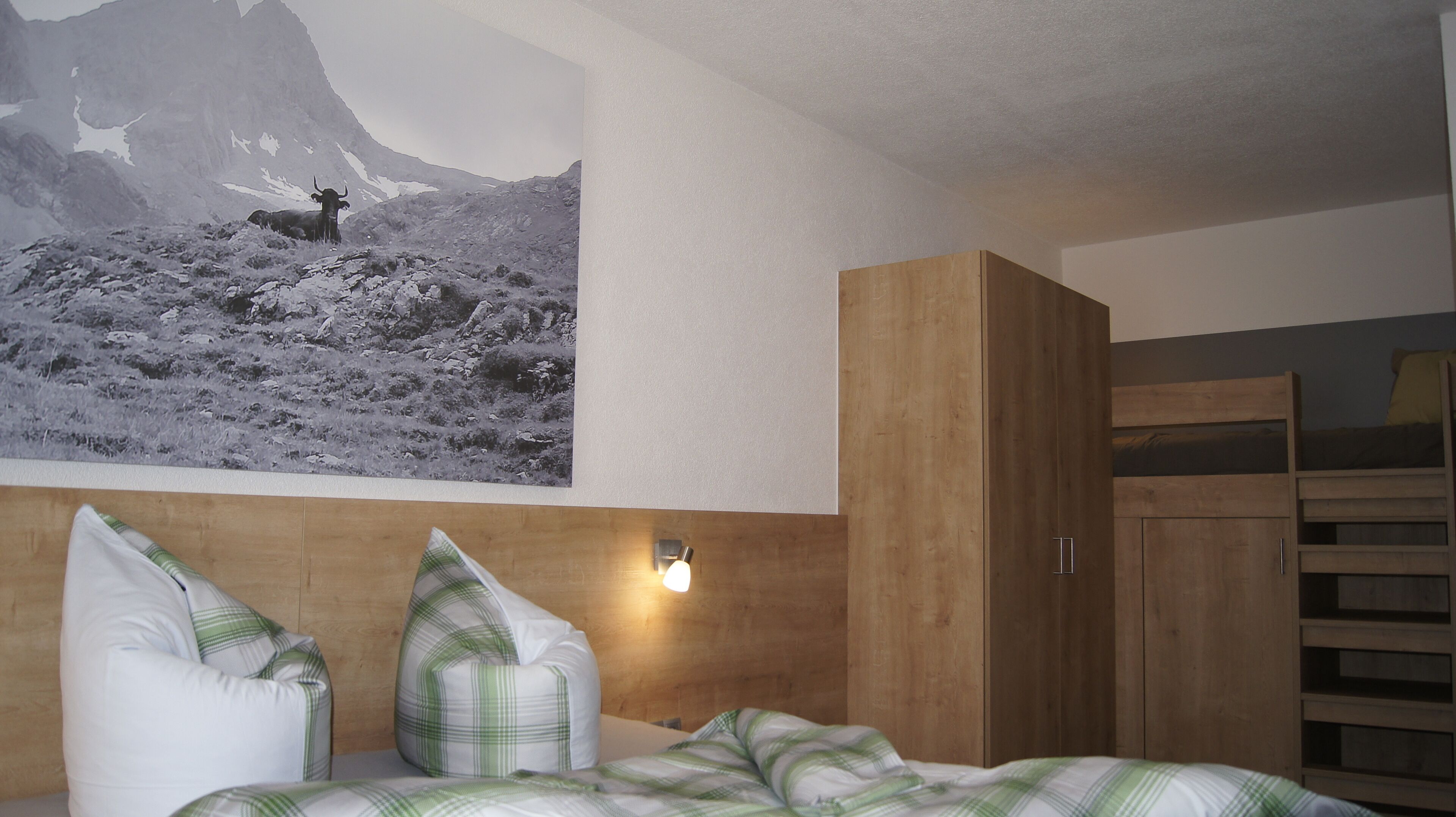 Ein Schlafzimmer mit einem Bett, Kissen, einem Holzschrank und einer Wandleuchte.