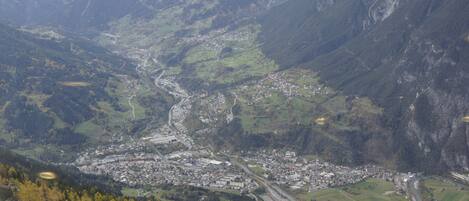 An aerial view of a valley with a town, roads, and surrounding mountains.
