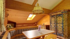 Ein gemütliches Holzhäuschen mit Essbereich, ausgestattet mit Tisch, Bänken, einem dekorativen Schrank und einem Oberlicht.