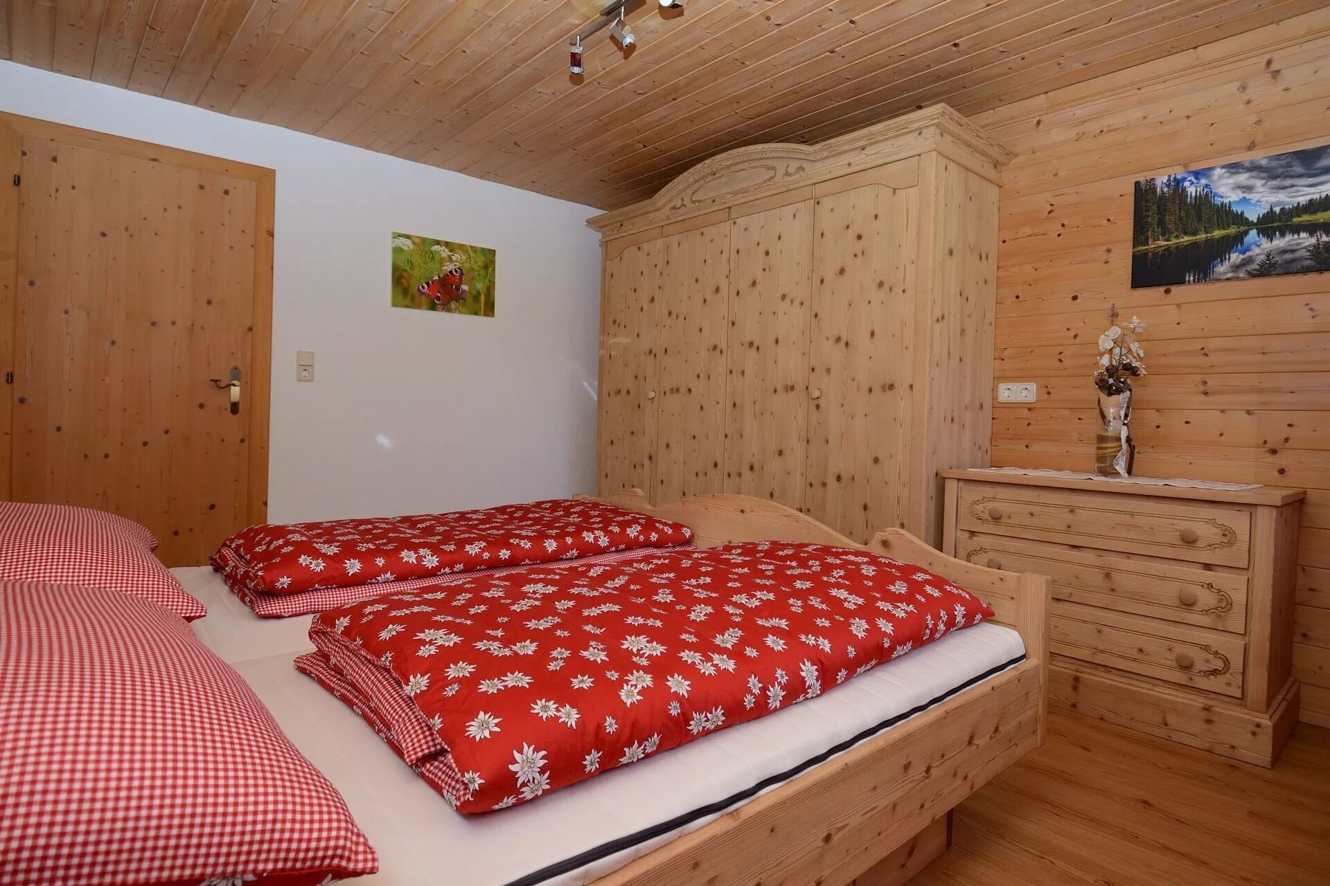 A wooden room with a bed, a dresser, and a painting on the wall.