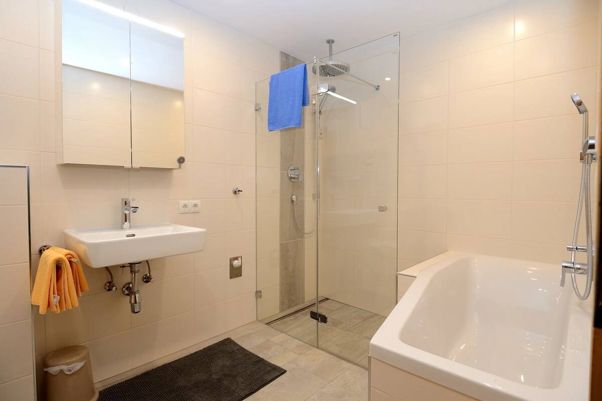 A modern bathroom with a glass-enclosed shower, a standalone bathtub, and a sink with a mirror above it.