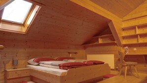 Ein gemütliches Schlafzimmer im Dachgeschoss mit Oberlicht, einem Holzbett, einem Nachttisch, einem Sessel und einer Heizung.