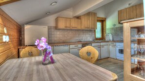 Eine moderne Küche mit Holzausstattung, einer zentralen Kochinsel und einer Glasvase mit Blumen.