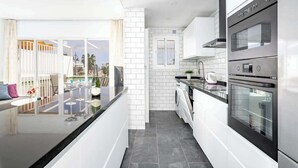 Una cocina moderna con armarios blancos, encimera negra y electrodomésticos de acero inoxidable.
