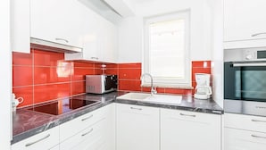 A modern kitchen with white cabinets, red tiles, a Bosch oven, a coffee maker, and a toaster. - Apartment Janko (Medulin)