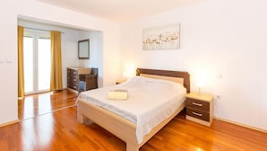 A bedroom with a wooden bed, bedside tables, a wardrobe, and a large window with curtains. - Apartment Janko (Medulin)