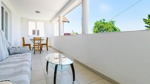 A balcony with a sofa, a glass table, and a dining set. - Apartment Janko (Medulin)