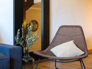 A modern room with a brown woven chair, a vase with branches, and a clock on the wall. - Cozy apartment Loredana in Poreč (Porec)