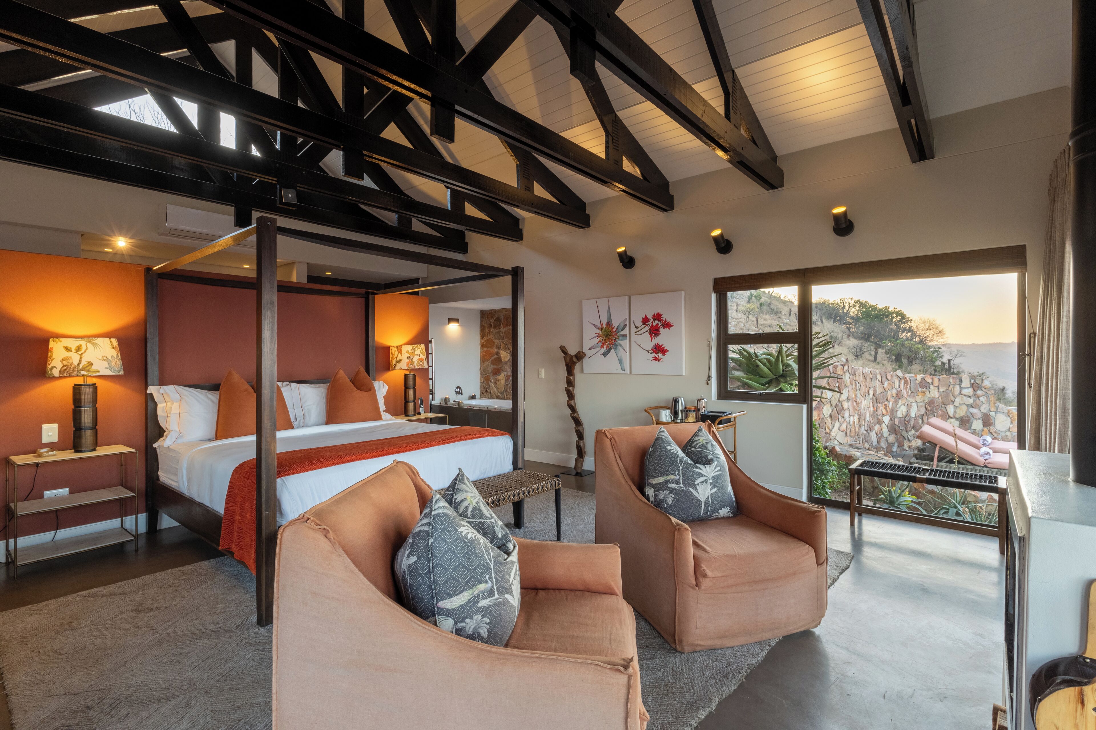 Un dormitorio moderno con una cama con dosel, dos sillones y un ventanal con vistas al exterior.