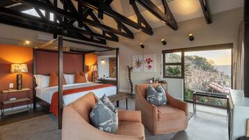 Un dormitorio moderno con una cama con dosel, dos sillones y un ventanal con vistas al exterior.