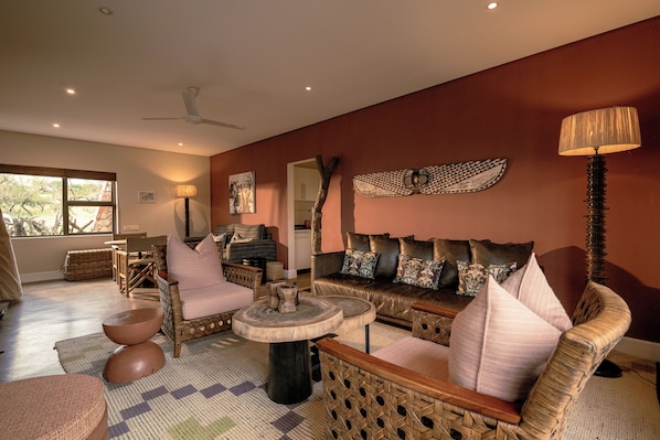 Una sala de estar acogedora con muebles de mimbre, una mesa redonda y un sofá con cojines.