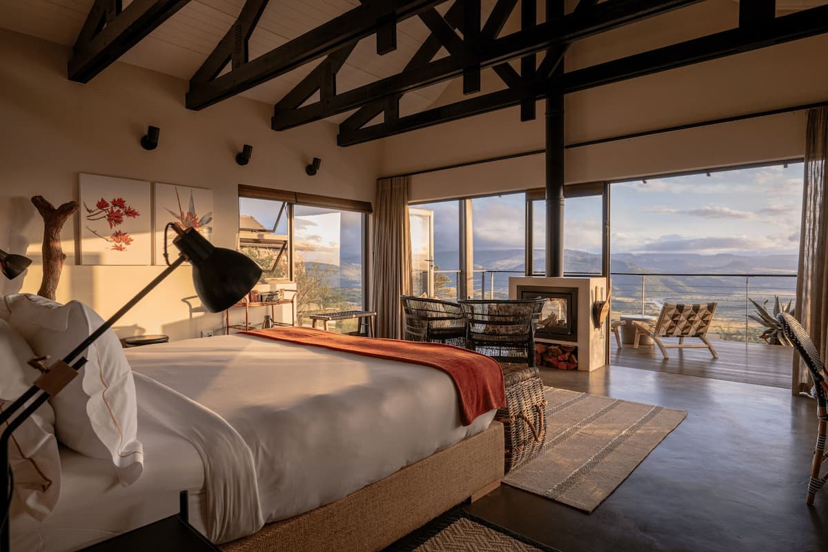 A bedroom with a large bed, a desk, and a balcony with a view.