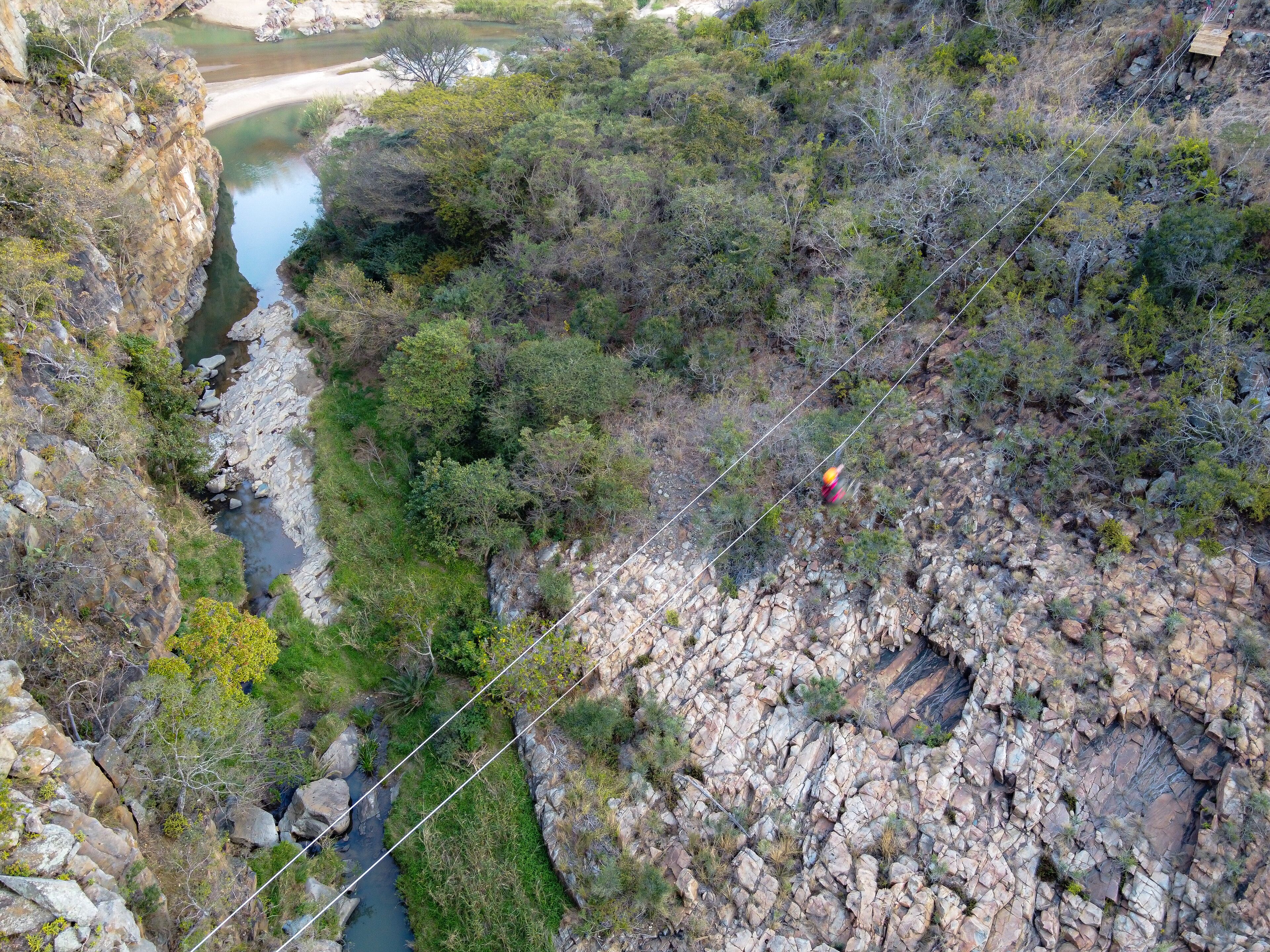 A rocky terrain with a suspension bridge and a river.