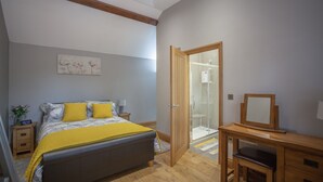 A bedroom with a bed, bedside table, and a wooden desk with a chair. - HEREFORDSHIRE – Little Oak: Charming Rural Cottage, Sleeps 2, Cozy Getaway (HEREFORD)