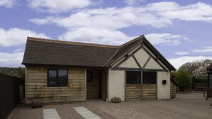A two-story wooden house with a sloped roof and a garage. - HEREFORDSHIRE – Little Oak: Charming Rural Cottage, Sleeps 2, Cozy Getaway (HEREFORD)