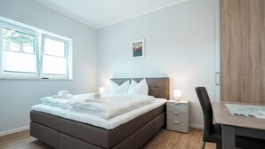 A modern bedroom with a bed, bedside tables, a desk, and a chair. - Haus Seeweg Geierswalde - Apartment 2 (Elsterheide)
