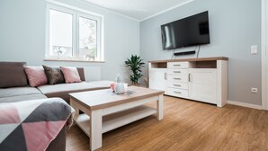 Una sala de estar moderna con un sofá, una mesa de centro, un televisor y un aparador.