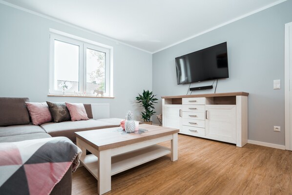Een moderne woonkamer met een bank, een salontafel, een televisie en een kast.