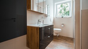 Un baño moderno con tocador de madera, un lavabo blanco y un inodoro.