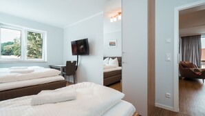 Habitación de hotel con dos camas, televisión, escritorio y vistas al exterior.