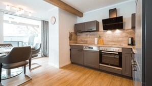 Una cocina moderna con suelo de madera, armarios empotrados, horno integrado y un comedor con mesa y sillas.