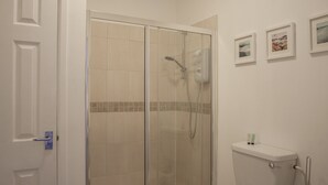 Un baño con ducha de vidrio, inodoro y lavamanos.