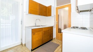 A compact kitchen with wooden cabinets, a white countertop, a sink, and a stove. - Beautiful view apartment Loreta (Labin)