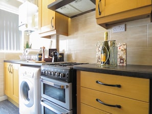 Enjoy cooking in this well-equipped kitchen with a stainless steel range hood, oven, and washing machine.