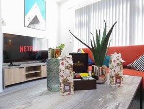 Relax in this stylish living room with a flat-screen TV, comfortable sofa, and a vase with a beautiful floral pattern.