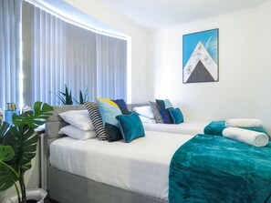 Relax in a serene space with a large bed, potted plant, and framed artwork.