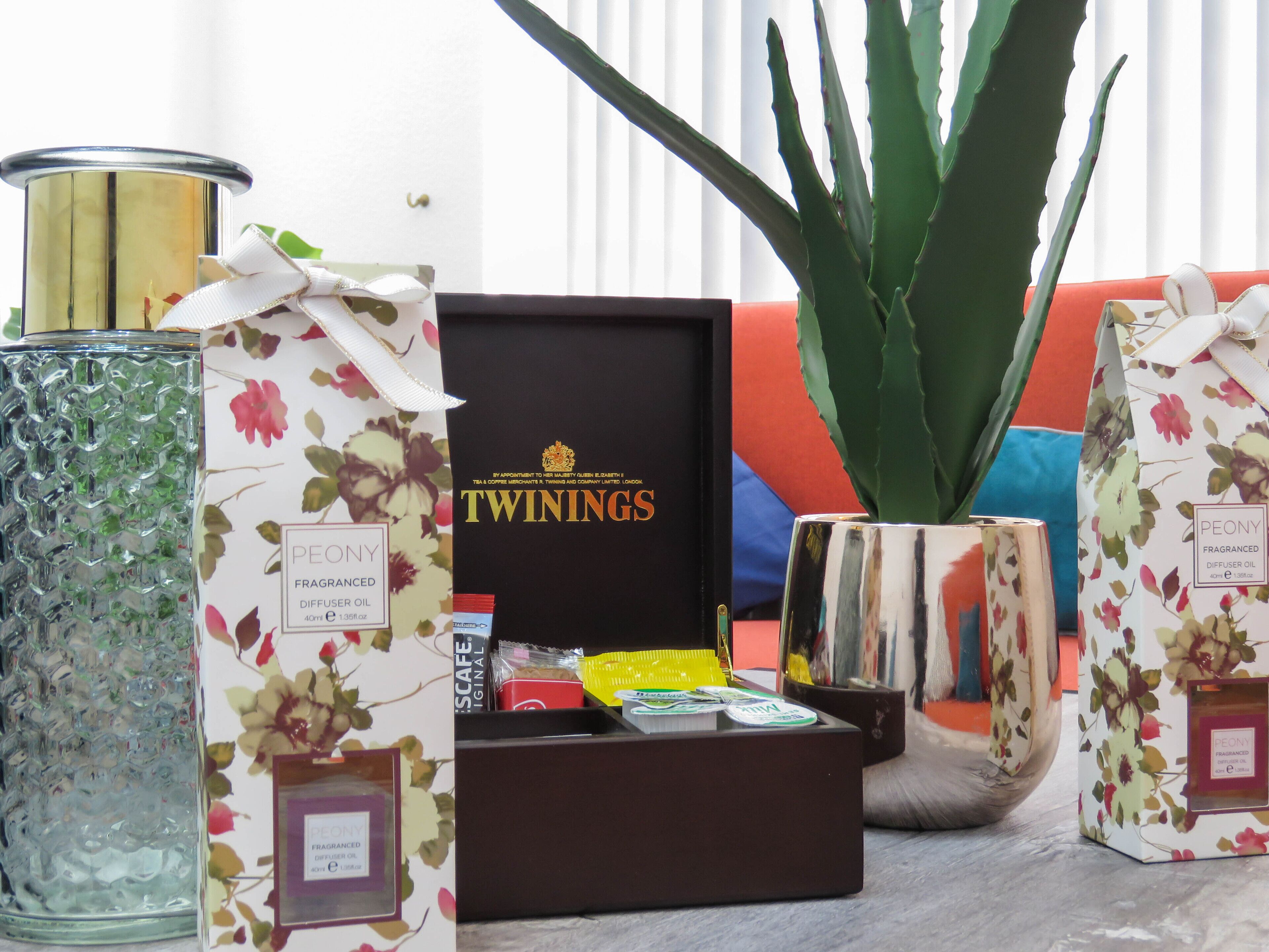 A variety of scented candles and diffusers, including brands like Twinings and Peony, arranged on a table.