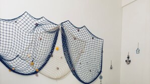 Una cama bien hecha con sábanas blancas, una mesita redonda pequeña y un adorno decorativo en la pared.
