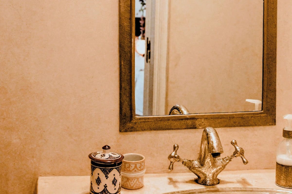 A bathroom with a sink, a mirror, and a towel rack.