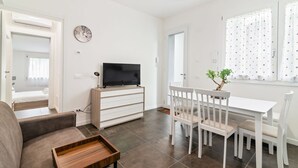 A modern living room with a sofa, TV, dining table, and chairs.