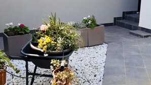 A potted plant arrangement on a gravel surface with a tiled floor and steps in the background.