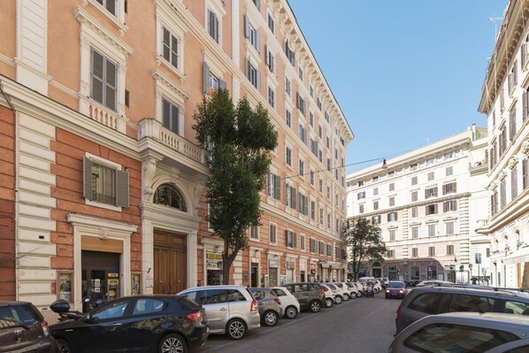 A street lined with parked cars and historic buildings with classical architecture.
