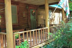 Uma cabana de madeira com varanda, porta decorada com uma guirlanda e uma bandeira.