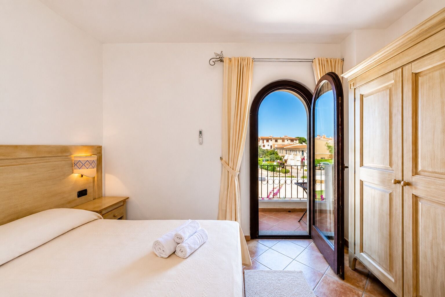 Ein Hotelzimmer mit Bett, Nachttisch und Blick auf den Balkon.