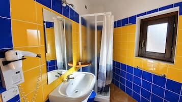 Une salle de bain avec un lavabo blanc, un miroir, une douche avec un rideau et une fenêtre avec un cadre en bois.