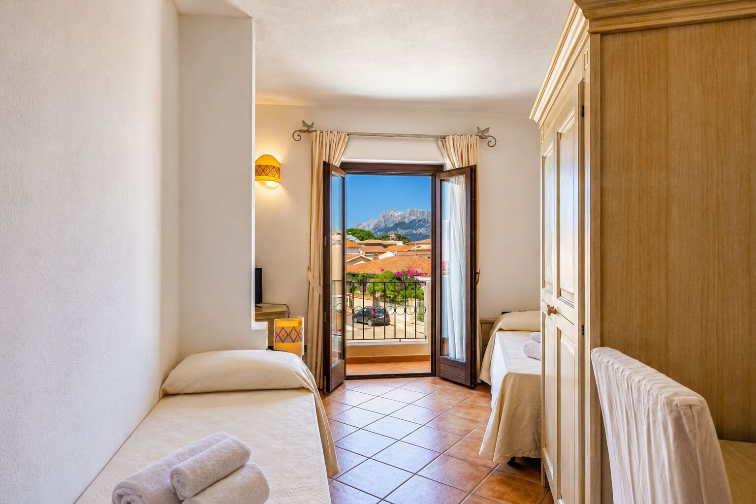 Ein Hotelzimmer mit Balkon, Bett, Nachttisch und Blick auf die Berge.